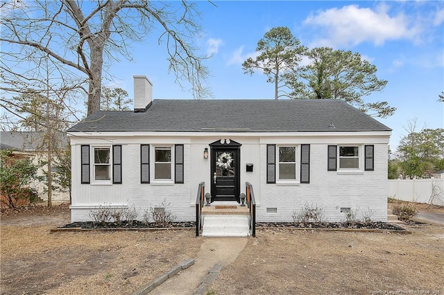 view of front of property featuring fence, a shingled roof, crawl space, brick siding, and a chimney