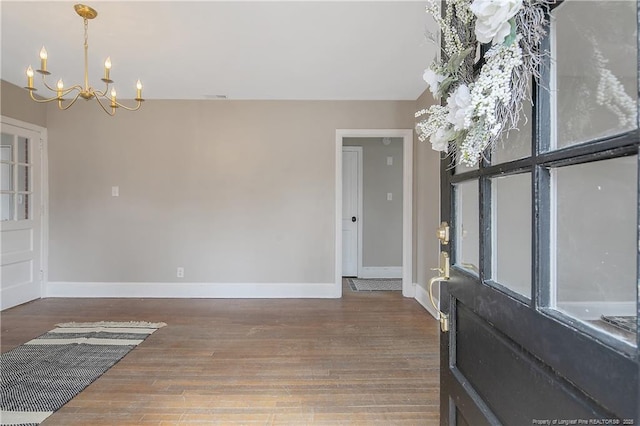 foyer featuring baseboards, an inviting chandelier, and wood finished floors