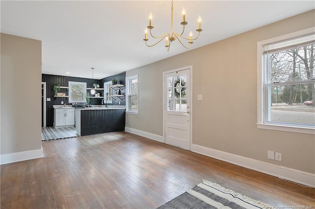 kitchen featuring a sink, baseboards, a notable chandelier, and hardwood / wood-style floors