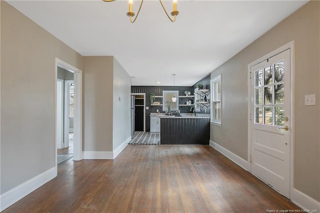 interior space featuring dark wood-type flooring, a peninsula, baseboards, and light countertops