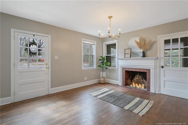 unfurnished living room with a wealth of natural light, a notable chandelier, and wood-type flooring