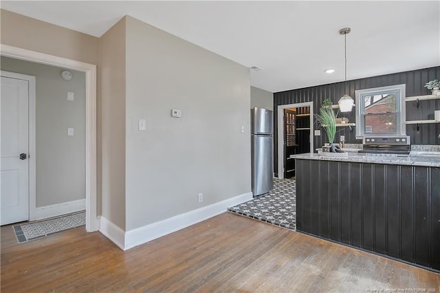 kitchen featuring light stone counters, wood finished floors, baseboards, open shelves, and appliances with stainless steel finishes