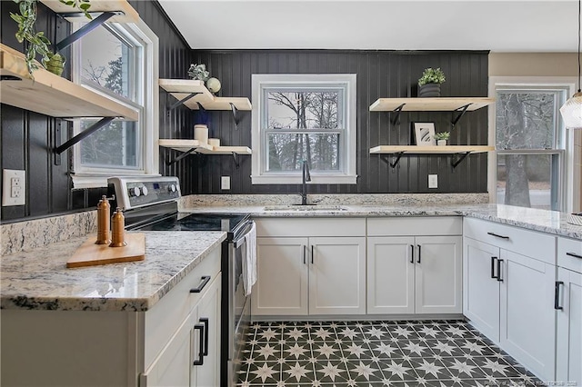 kitchen with light stone countertops, open shelves, a sink, stainless steel range with electric stovetop, and white cabinetry