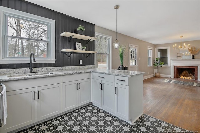 kitchen with a notable chandelier, a peninsula, pendant lighting, and a sink