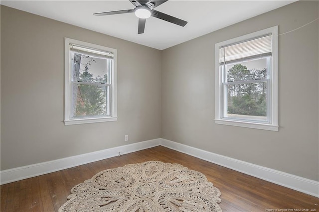 unfurnished room featuring plenty of natural light, wood finished floors, and baseboards