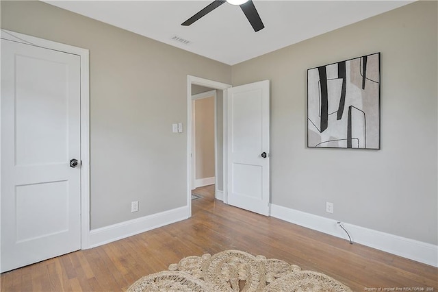 bedroom featuring visible vents, a ceiling fan, baseboards, and wood finished floors