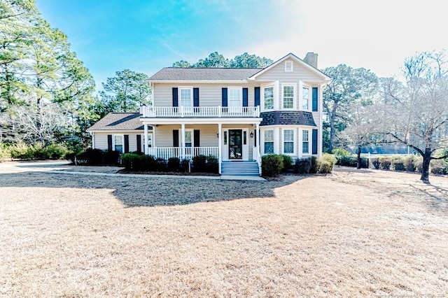 view of front of home featuring a porch, a chimney, and a balcony