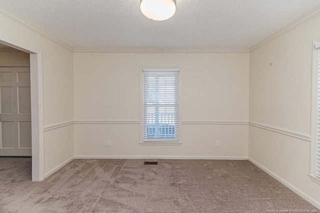 empty room with a textured ceiling, crown molding, baseboards, and carpet floors