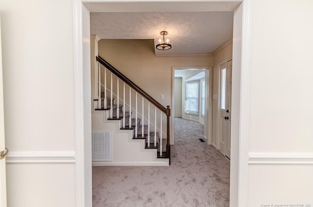 foyer entrance with visible vents, baseboards, carpet, stairway, and a textured ceiling