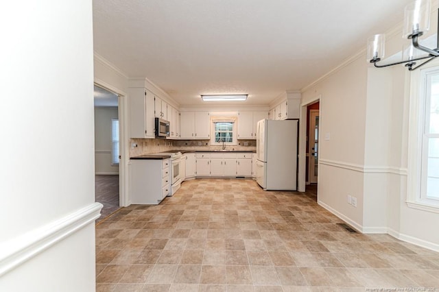 kitchen with tasteful backsplash, white cabinets, white appliances, and a sink