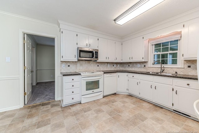 kitchen with white appliances, white cabinets, dark countertops, and a sink