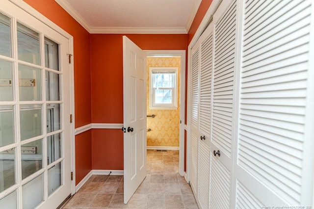 hall featuring light tile patterned floors, wallpapered walls, baseboards, and ornamental molding