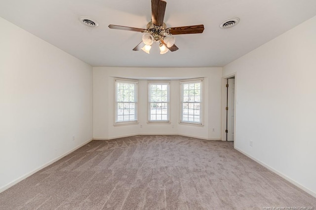 carpeted empty room with visible vents, baseboards, and a ceiling fan