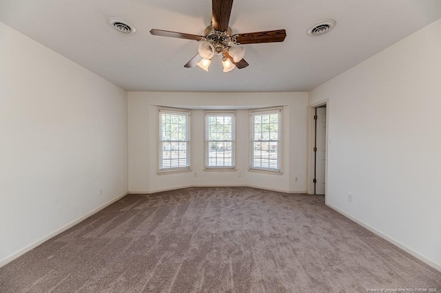 empty room featuring visible vents, carpet flooring, baseboards, and ceiling fan