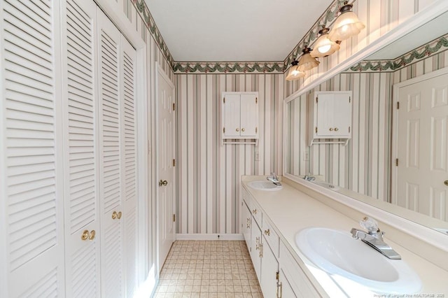 full bathroom with wallpapered walls, a closet, and a sink