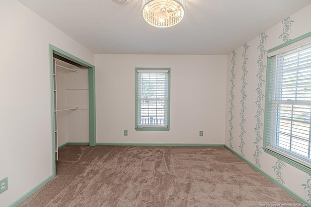 unfurnished bedroom featuring baseboards, wallpapered walls, and carpet