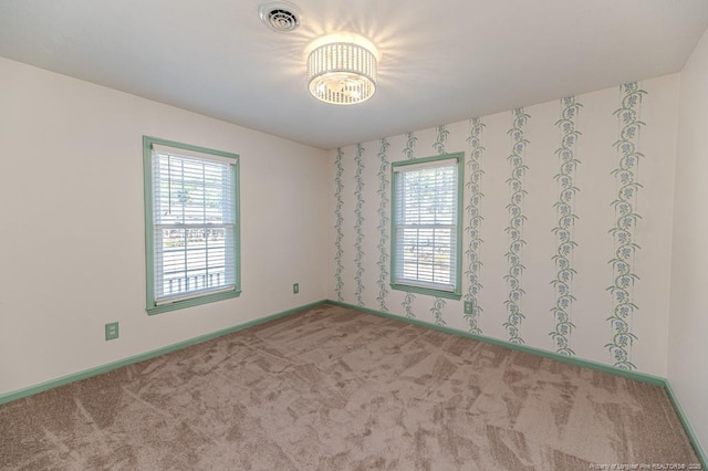 carpeted spare room with visible vents and baseboards