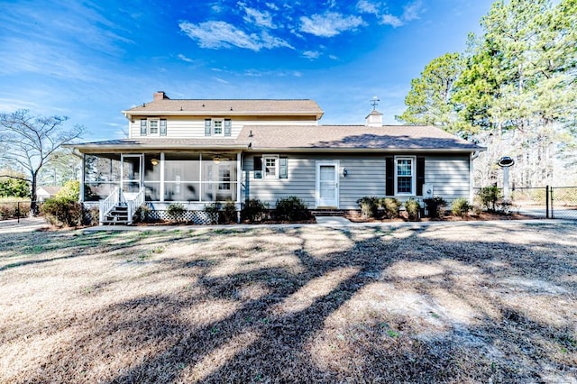 back of house featuring a gate, a chimney, fence, and a sunroom