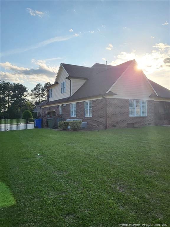 back of property featuring crawl space, brick siding, a yard, and fence