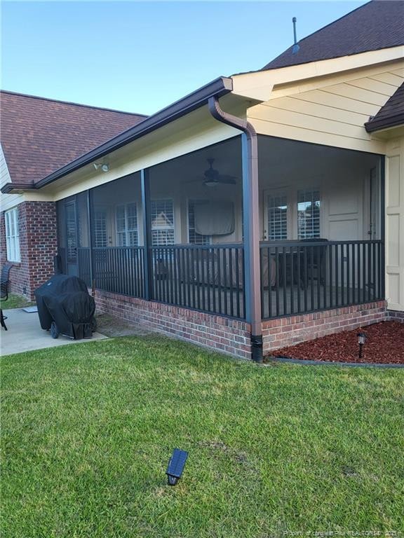 view of home's exterior featuring a shingled roof, a yard, and a sunroom