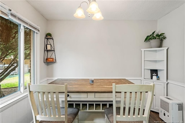 dining space with a chandelier, a healthy amount of sunlight, a textured ceiling, and dark wood-style flooring