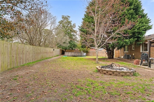 view of yard with cooling unit, a fire pit, and a fenced backyard