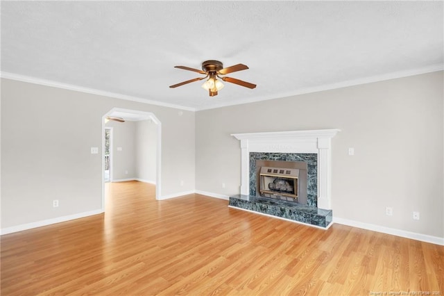 unfurnished living room with ornamental molding, a ceiling fan, light wood-type flooring, and baseboards