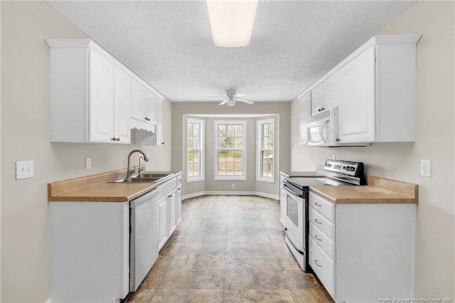 kitchen with dishwashing machine, a ceiling fan, white microwave, stainless steel electric range, and a sink