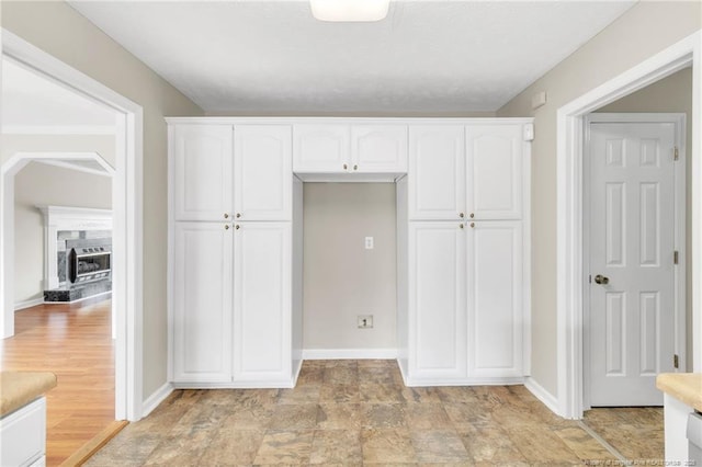 interior space with a closet, a fireplace with raised hearth, stone finish flooring, and baseboards