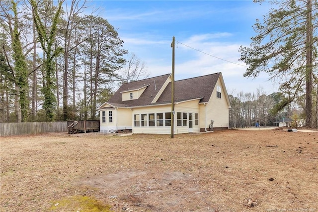 back of property with a deck, fence, and a shingled roof