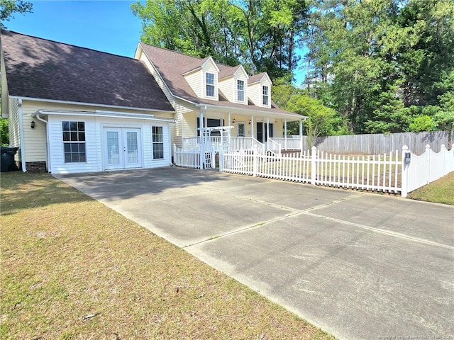 new england style home featuring fence, roof with shingles, a front lawn, a porch, and french doors