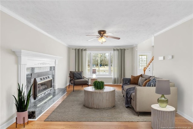 living room with ceiling fan, a textured ceiling, a fireplace, stairway, and heating unit
