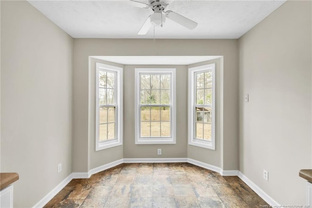 interior space featuring baseboards, ceiling fan, and stone finish floor