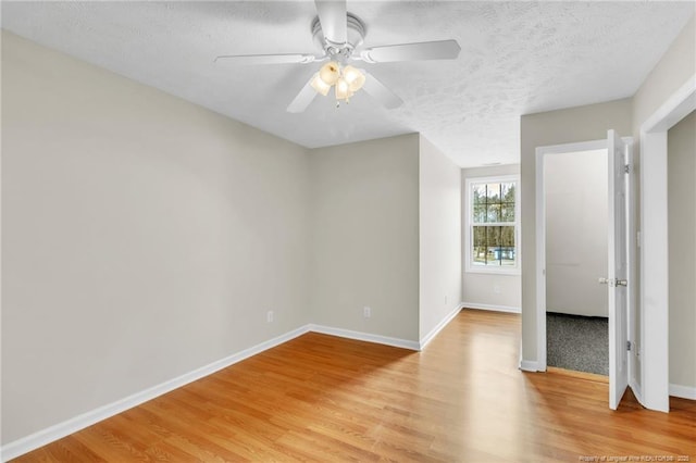 unfurnished bedroom featuring light wood-type flooring, a textured ceiling, baseboards, and ceiling fan