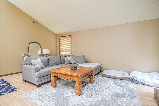 living room featuring lofted ceiling, light wood-style floors, visible vents, and baseboards