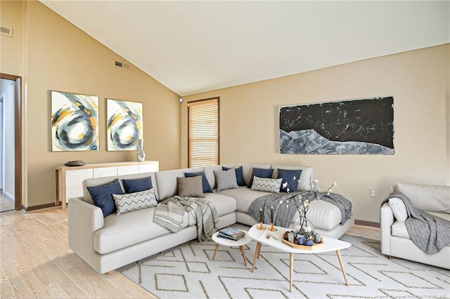 living area with lofted ceiling, wood finished floors, visible vents, and baseboards