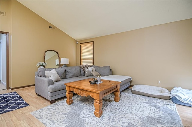 living area with lofted ceiling, light wood-style flooring, and visible vents