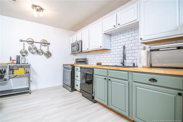 kitchen featuring backsplash, butcher block countertops, appliances with stainless steel finishes, white cabinets, and a sink