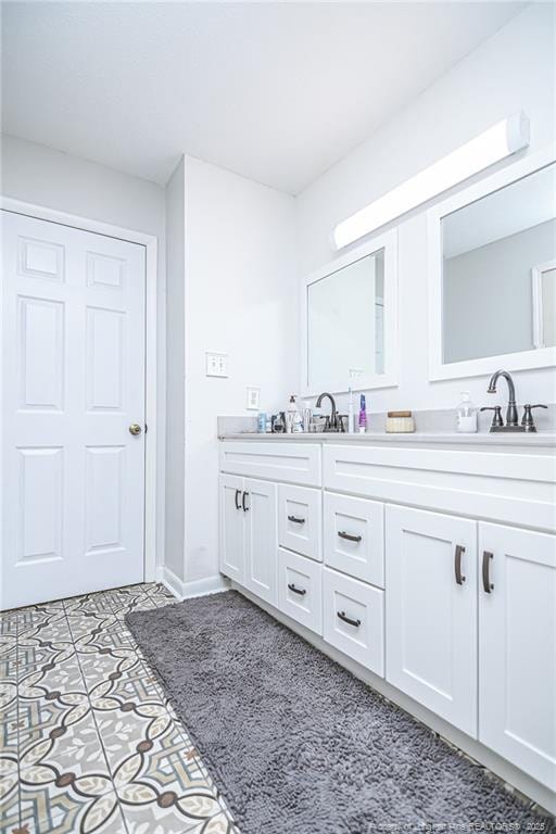 full bathroom with a sink, double vanity, and tile patterned flooring