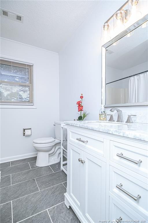 bathroom with vanity, toilet, visible vents, and a textured ceiling