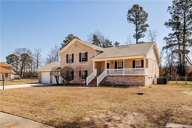 tri-level home with a porch, fence, concrete driveway, a garage, and brick siding