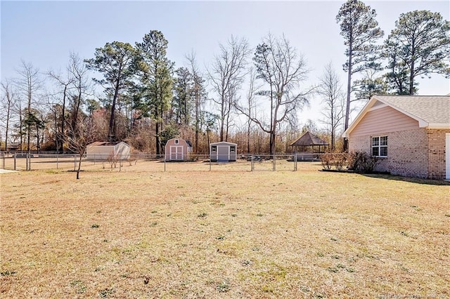 view of yard featuring an outbuilding, fence, and a shed