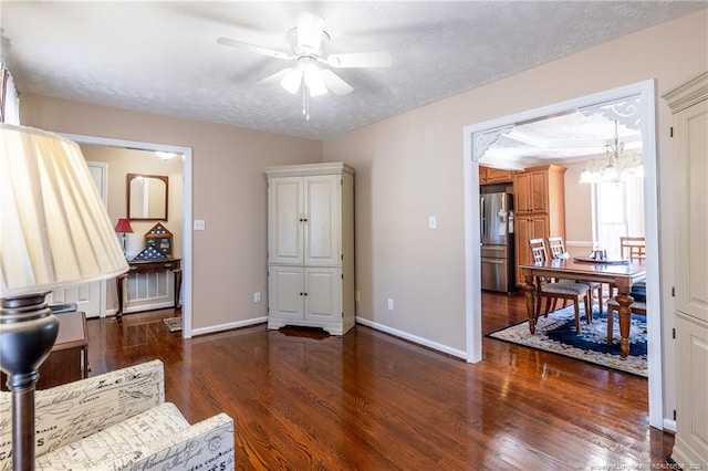 office area with ceiling fan with notable chandelier, a tray ceiling, a textured ceiling, wood finished floors, and baseboards