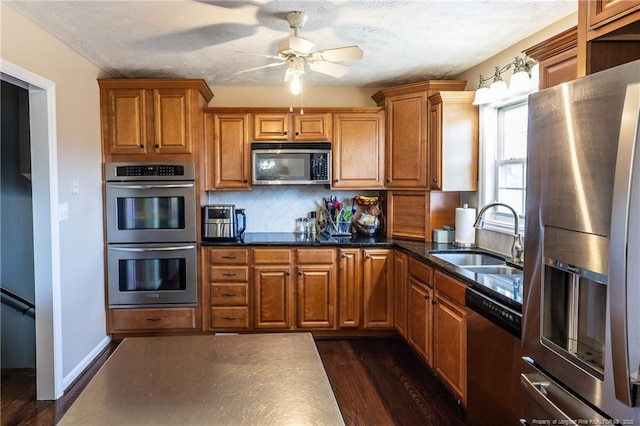 kitchen with ceiling fan, brown cabinets, appliances with stainless steel finishes, and a sink