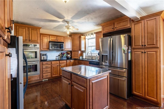 kitchen with a sink, stainless steel appliances, brown cabinets, and a ceiling fan