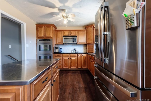 kitchen with brown cabinetry, backsplash, appliances with stainless steel finishes, and ceiling fan