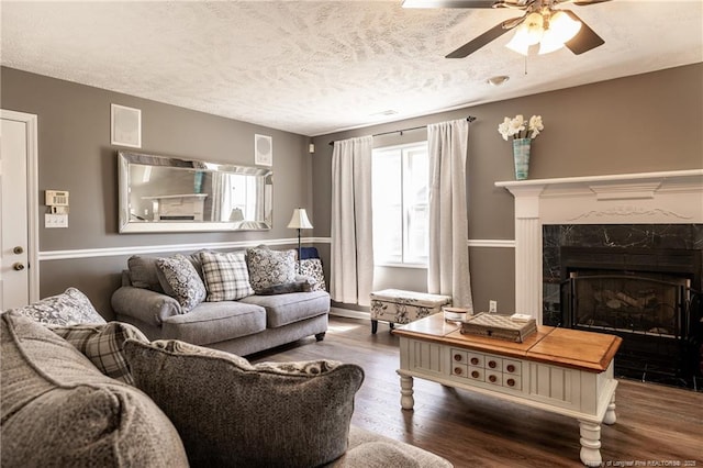 living room with a textured ceiling, a premium fireplace, wood finished floors, and ceiling fan