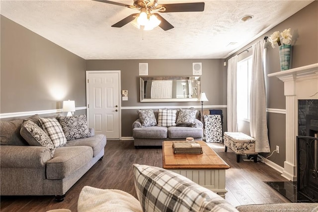 living room with baseboards, a fireplace, wood finished floors, a textured ceiling, and a ceiling fan