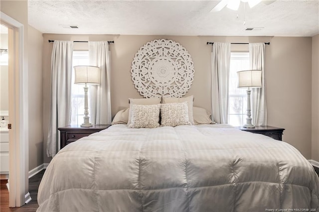 bedroom featuring visible vents, multiple windows, a textured ceiling, and wood finished floors