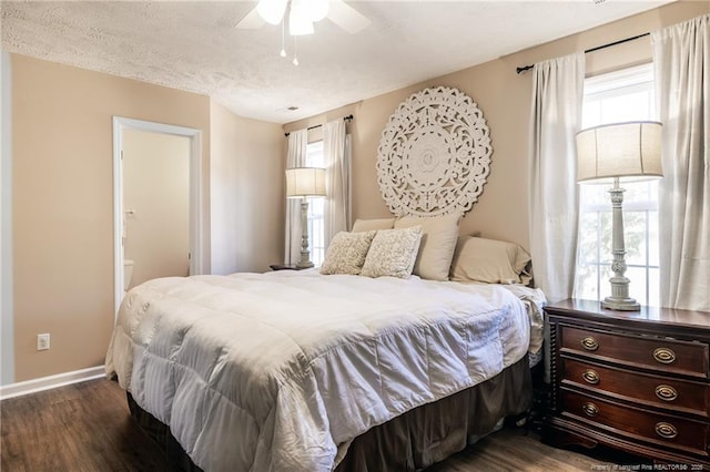 bedroom with a ceiling fan, baseboards, dark wood finished floors, ensuite bathroom, and a textured ceiling